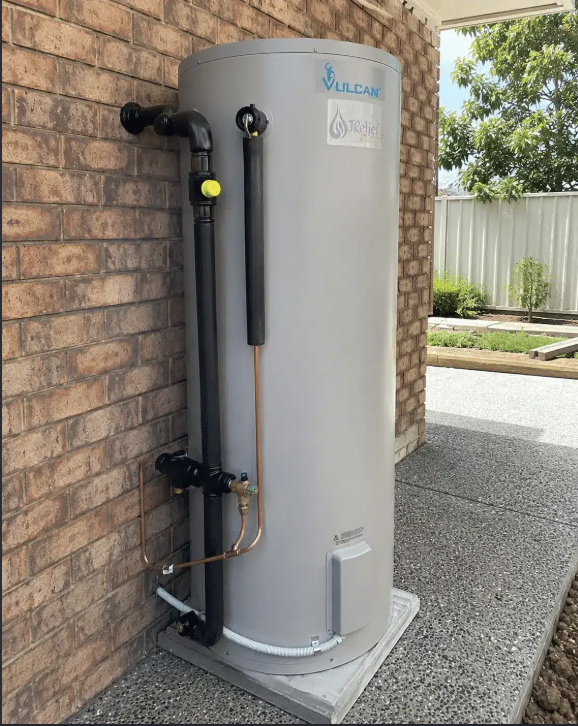 Plumber Melbourne inspecting a Vulcan storage hot water system beside a brick wall